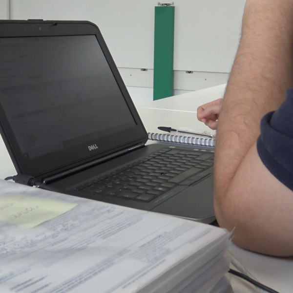 icona fotografica data entry, un operatore inserisce a computer dei dati presenti su carta